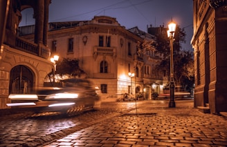 Evening shot of a car driving through Rome’s historic streets, city lights glowing.