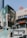 A modern commercial building featuring large glass windows, prominently displaying logos for Starbucks and TGI Fridays. The area includes outdoor signage for a Caribbean Cinemas and other shops. A set of stairs decorated with colorful designs leads up to the building entrance.