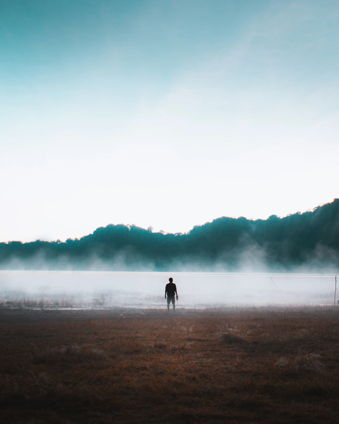 Person standing on the misty shore of a highland lake in Bali at dawn