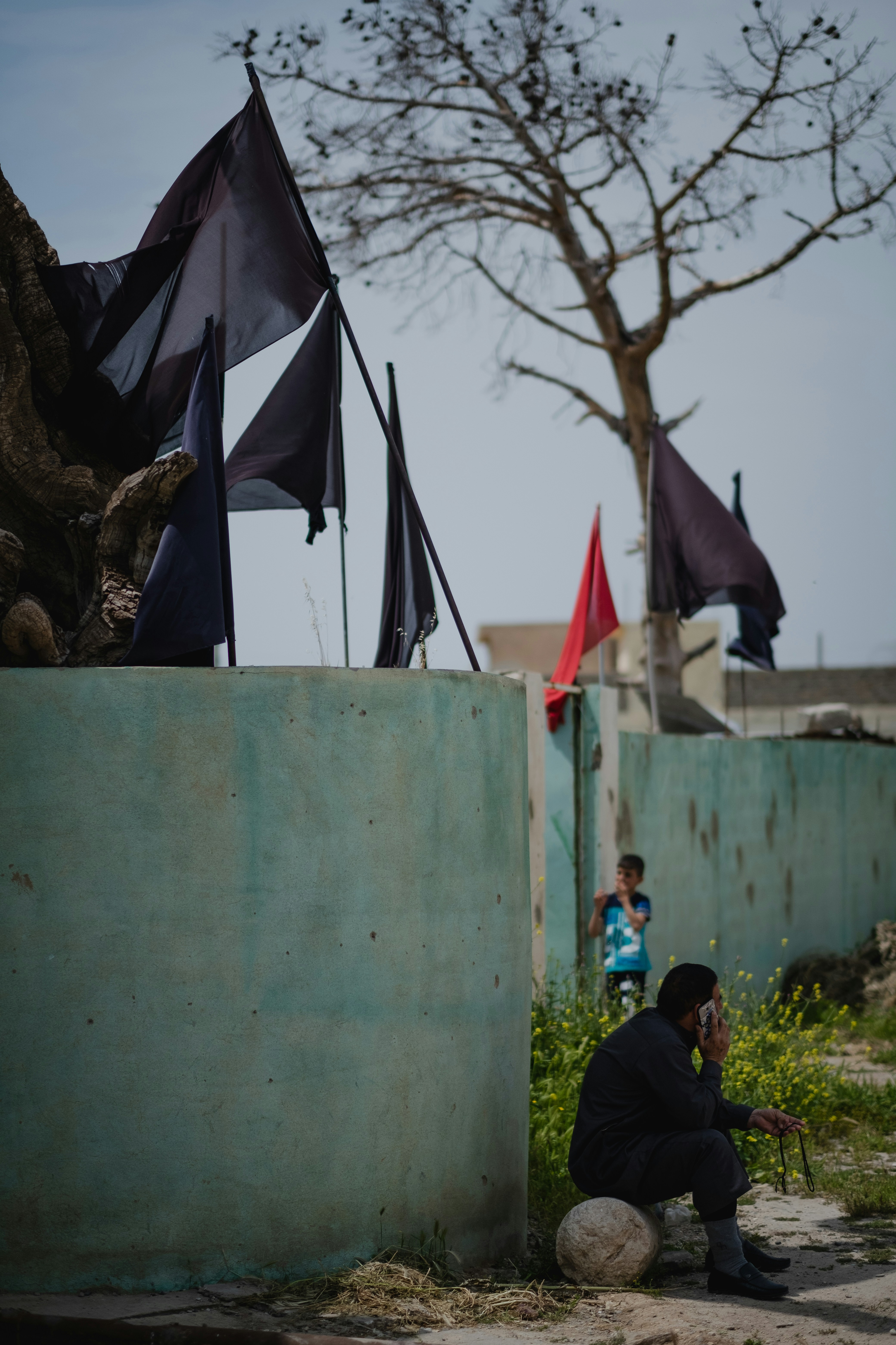 man in black jacket sitting on brown rock near white wall during daytime