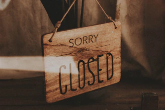 A closed sign hanging on a rustic wooden door with soft natural light.