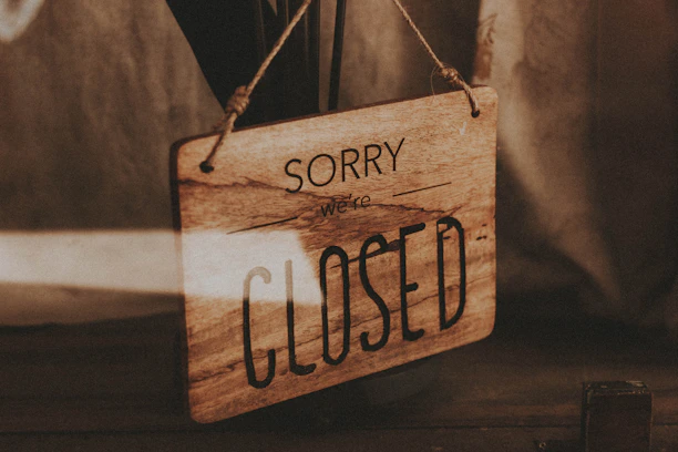A closed sign hanging on a rustic wooden door with soft natural light.