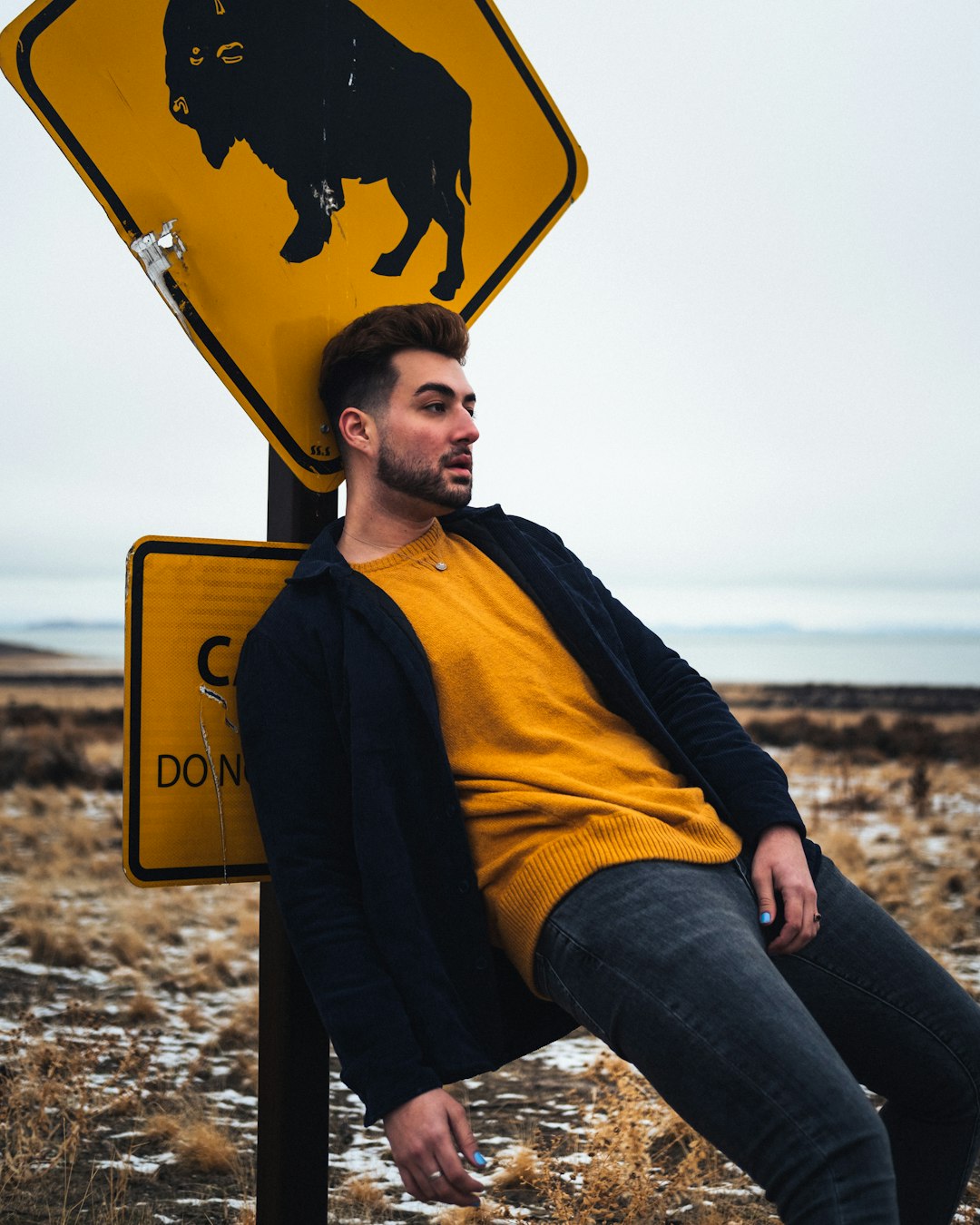 man in yellow and black jacket and blue denim jeans sitting on yellow surfboard during daytime