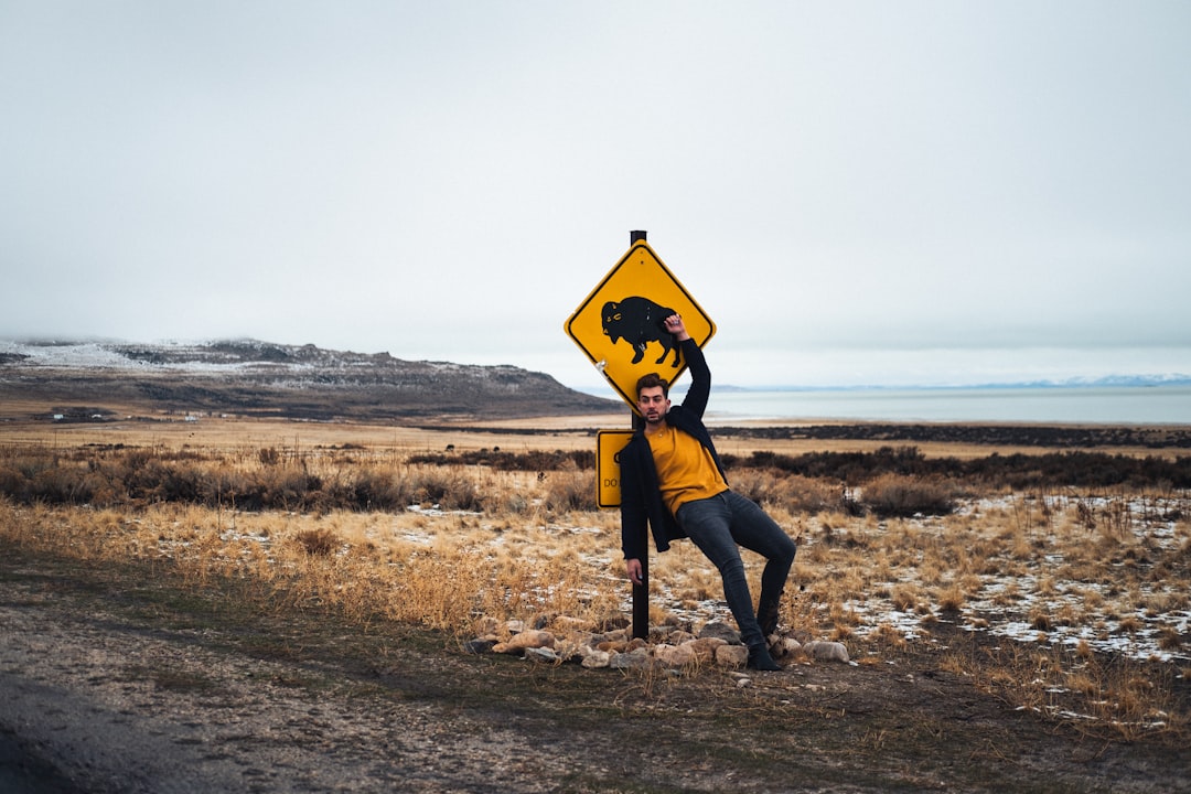 person in black jacket and black pants holding yellow and black road sign