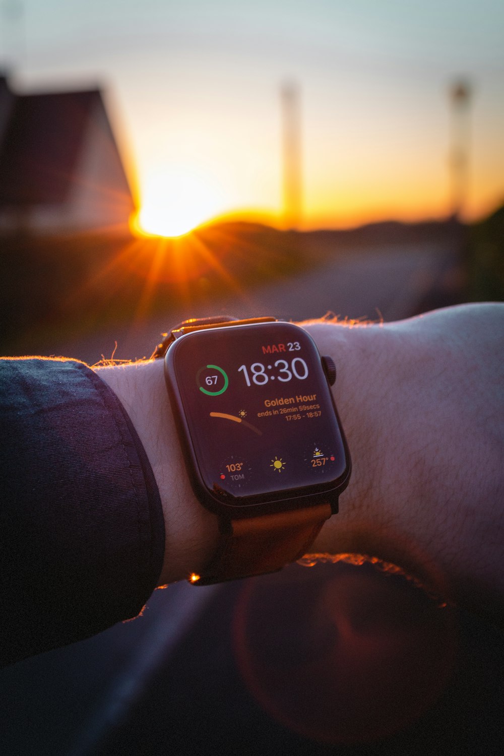 Someone checking the time on their Apple watch with a sun set in the background
