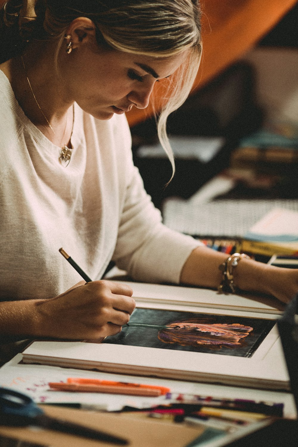 woman in white long sleeve shirt writing on white paper