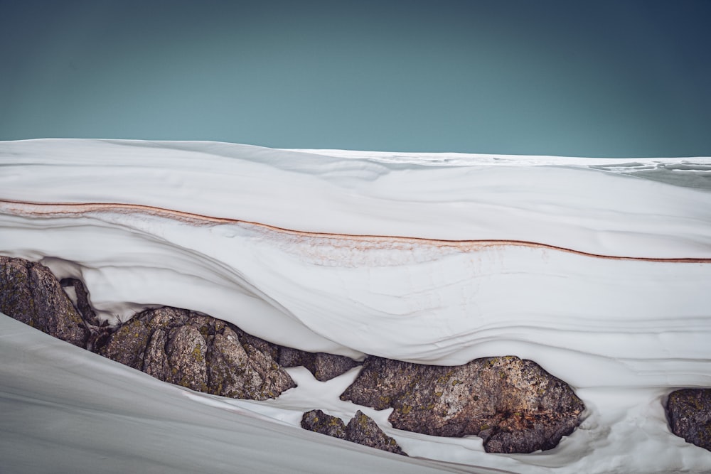 formazione rocciosa marrone sul campo di neve bianca durante il giorno