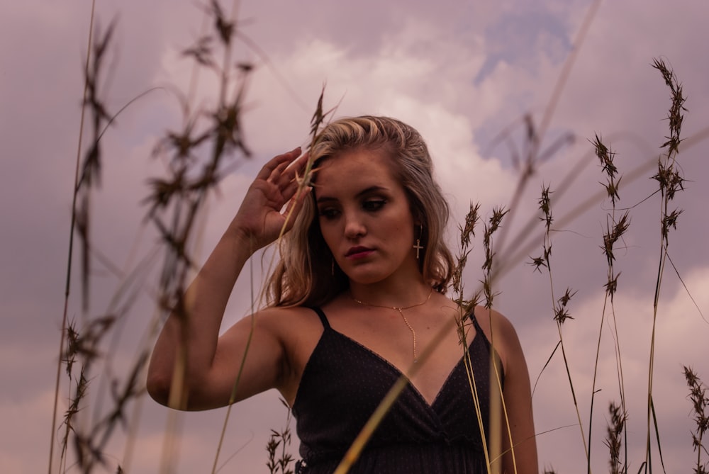 woman in black spaghetti strap top standing on brown grass field during daytime