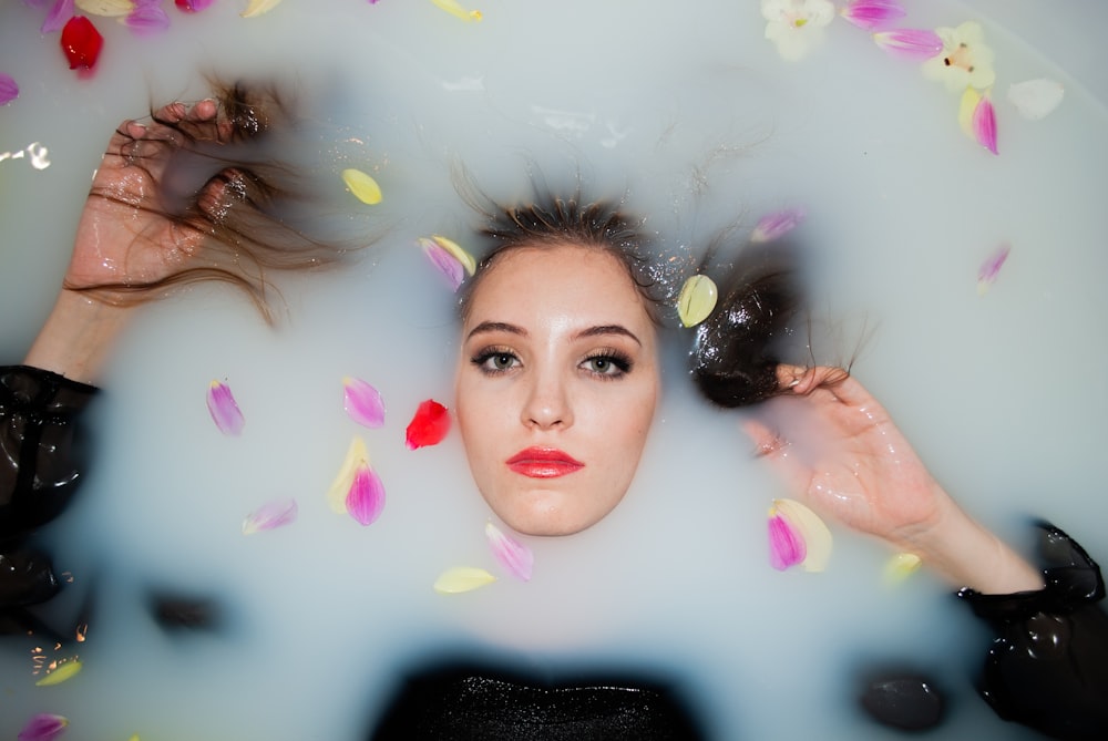 girl in pink lipstick lying on white and pink floral textile