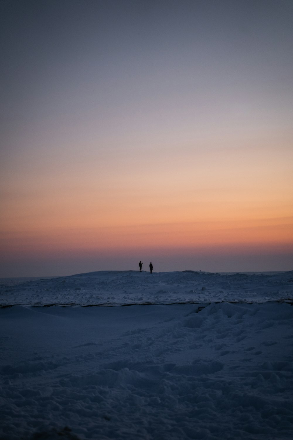 person standing on white sand during sunset