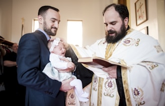 Religious events photography in Toronto, man in black suit holding baby in white dress
