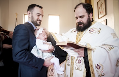 Religious events photography in Toronto, man in black suit holding baby in white dress