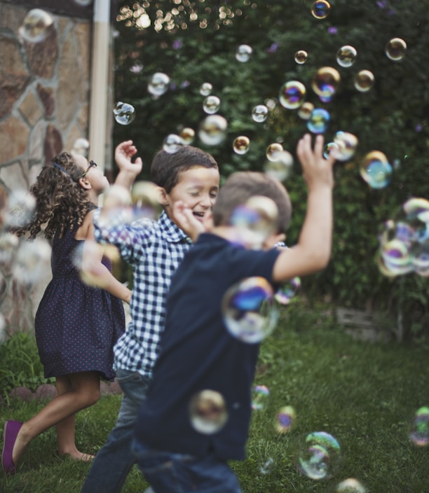 boy in blue and white polka dot shirt playing bubbles
