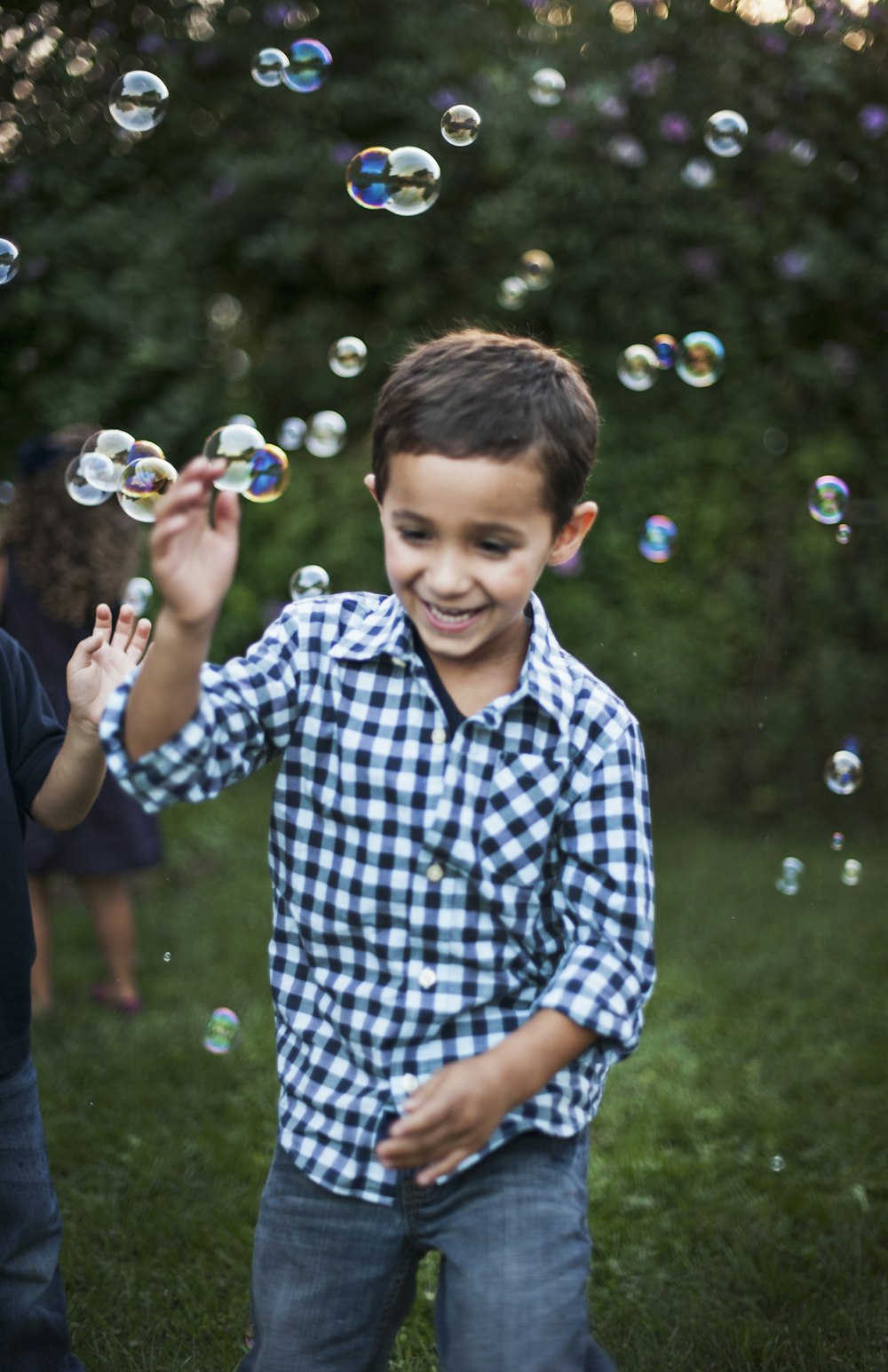 boy in blue and white plaid dress shirt playing bubbles