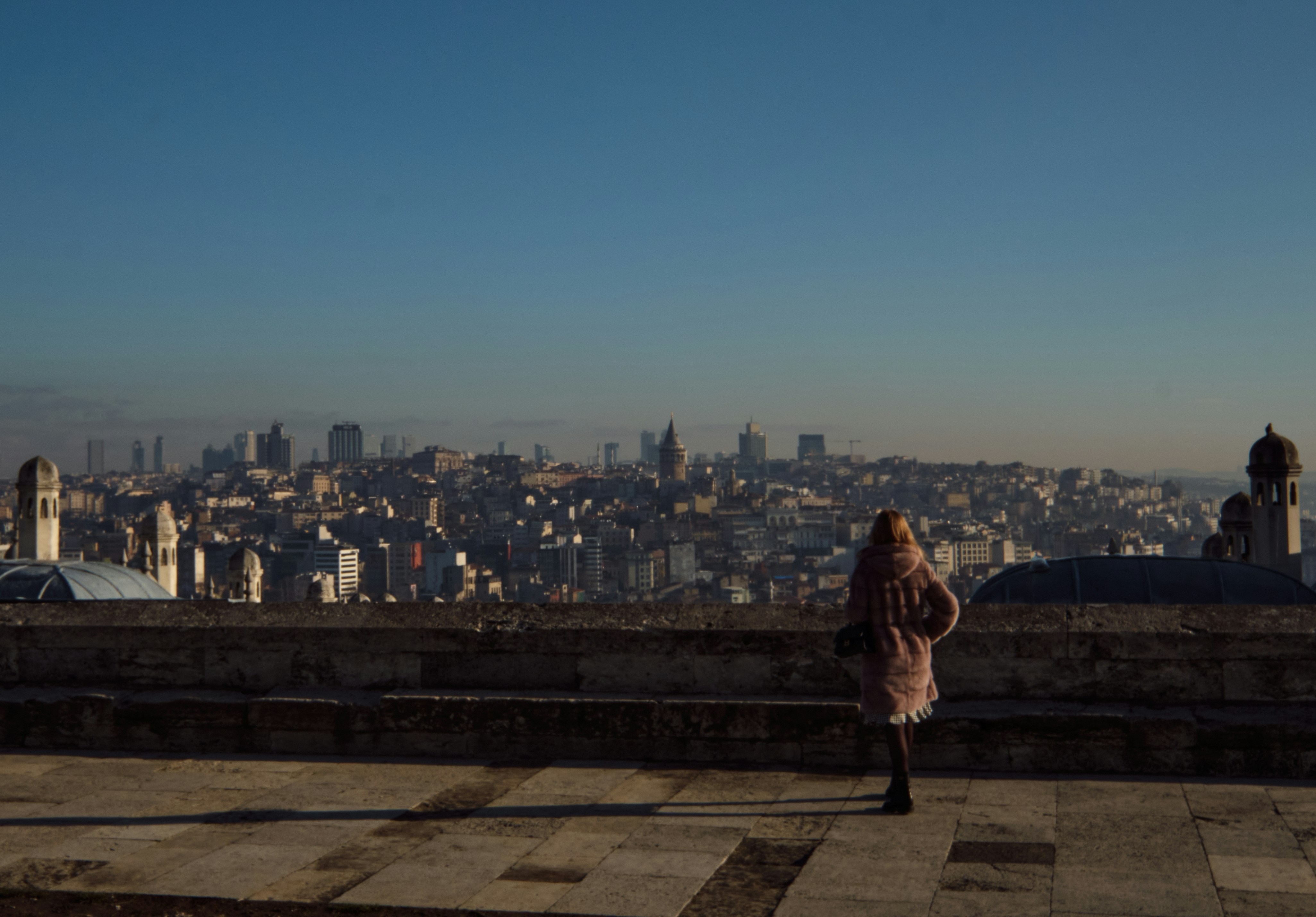 woman in brown coat standing on top of building during daytime