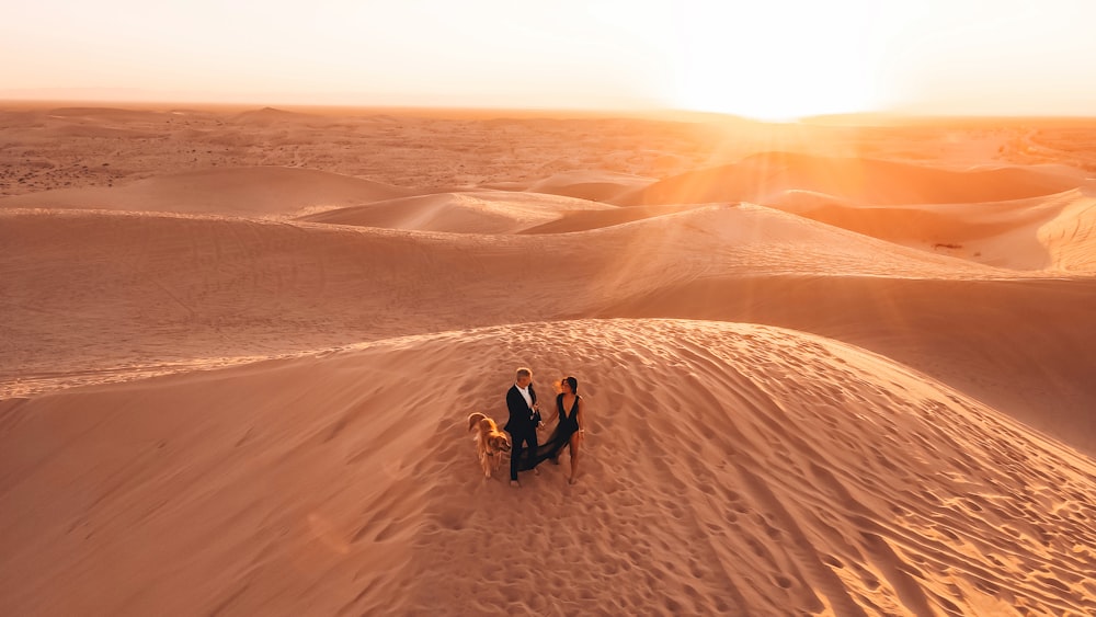 2 people sitting on sand dunes during daytime