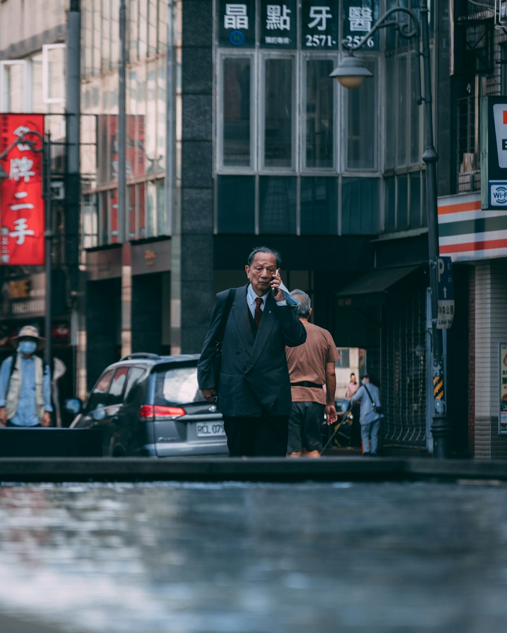 man in black suit standing beside black car during daytime