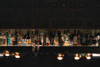 A cozy corner of the bar with amber lighting highlighting whiskey bottles on wooden shelves.