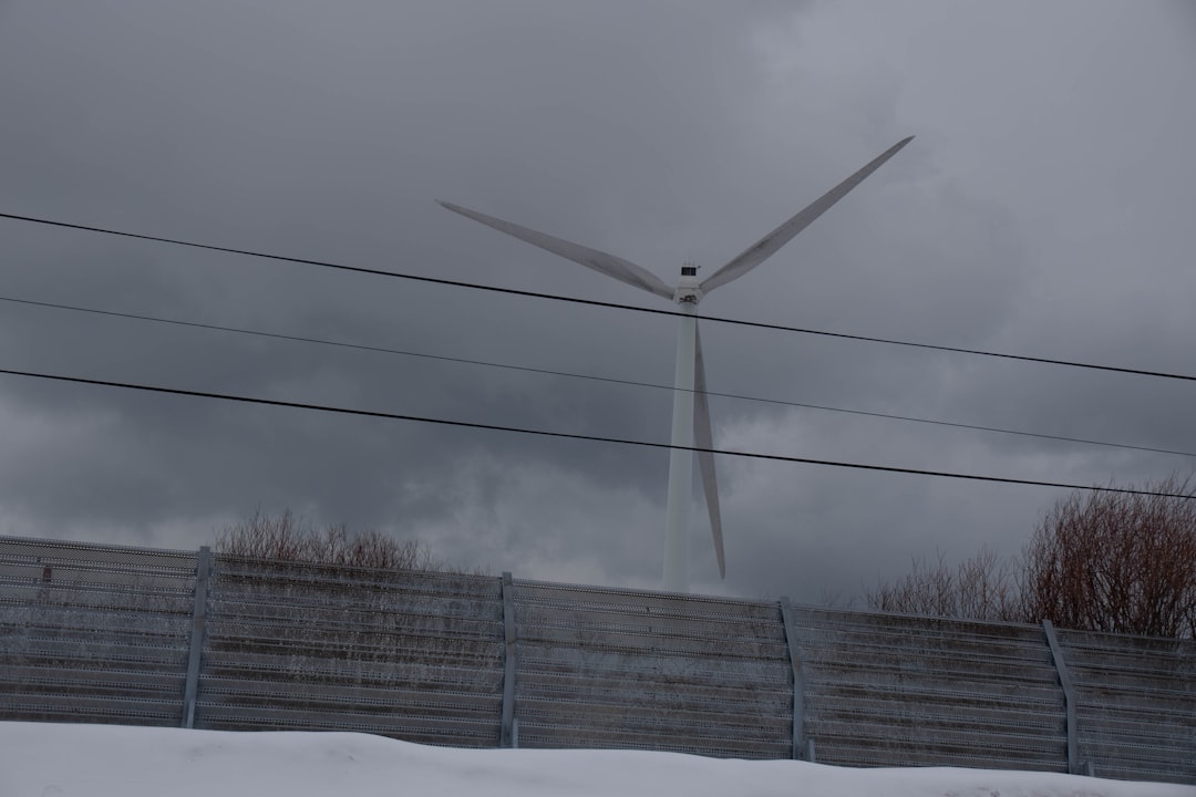 white wind turbine under gray cloudy sky