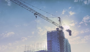 Construction workers discussing plans next to building materials at a sunny job site.