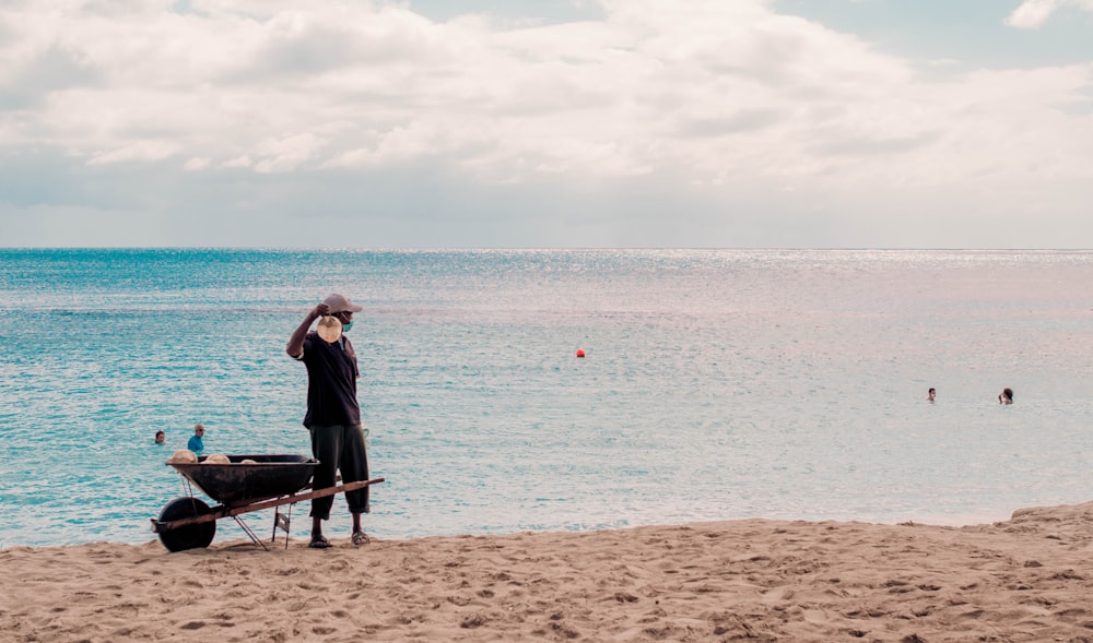 Hombre con camisa y pantalones negros de pie en la orilla de la playa durante el día