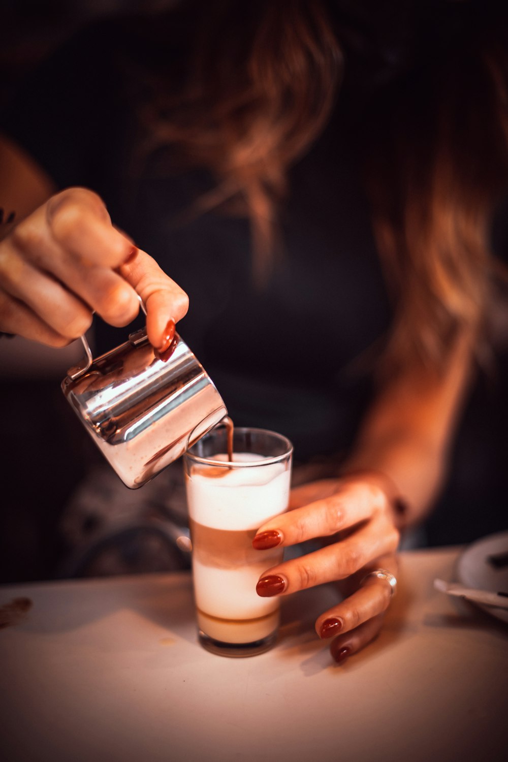 person holding clear drinking glass with white liquid