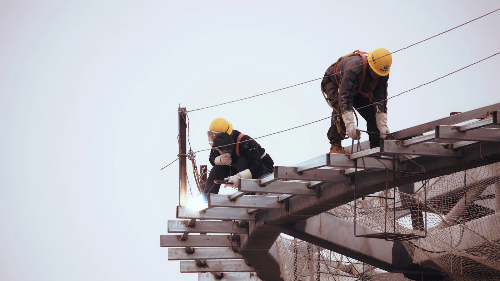 A worker in a yellow hard hat on a rooftop beside a solar array