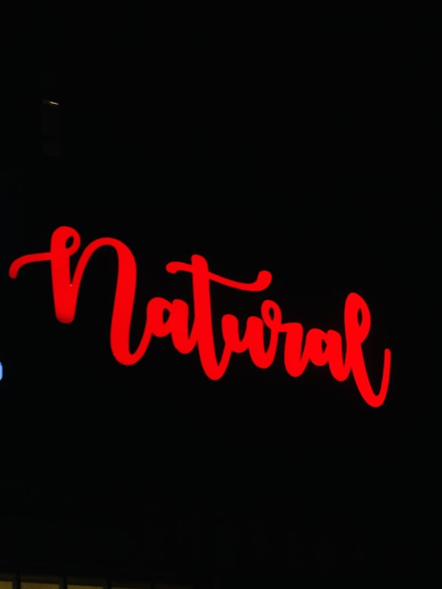 The image features the word 'Natural' written in bold, flowing red script against a black background.