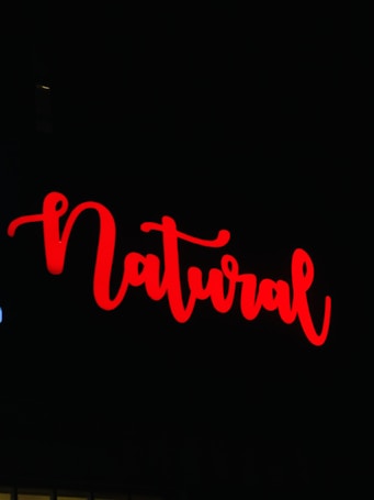 The image features the word 'Natural' written in bold, flowing red script against a black background.