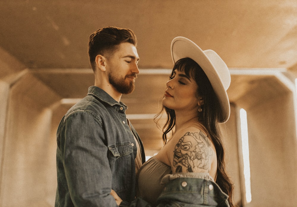 man in blue denim jacket standing beside woman in white fedora hat