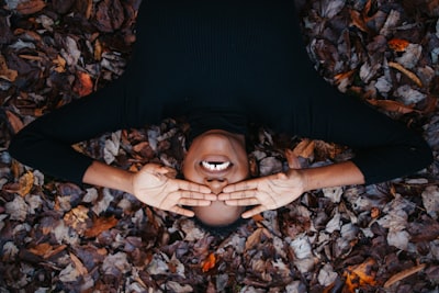 woman in black long sleeve shirt lying on dried leaves silly zoom background