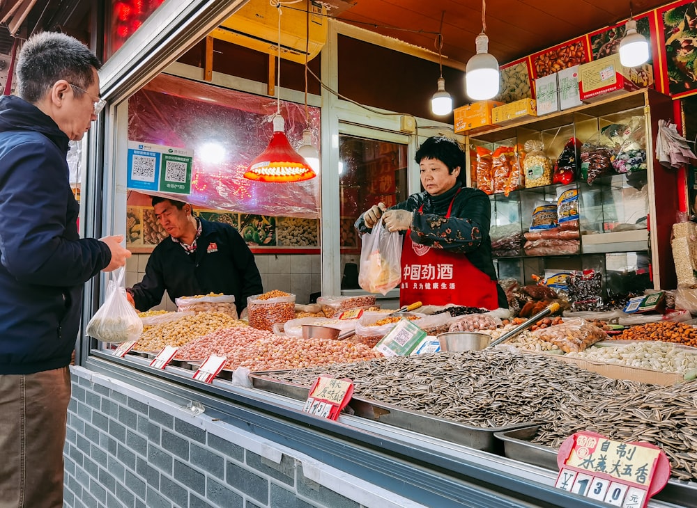 man in green jacket standing in front of food display counter