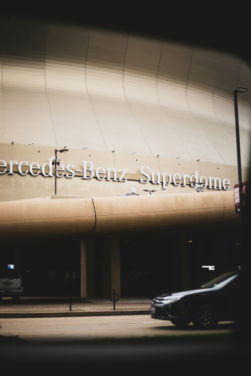 a car driving past a large building with a sign that reads mercedes benz supergram