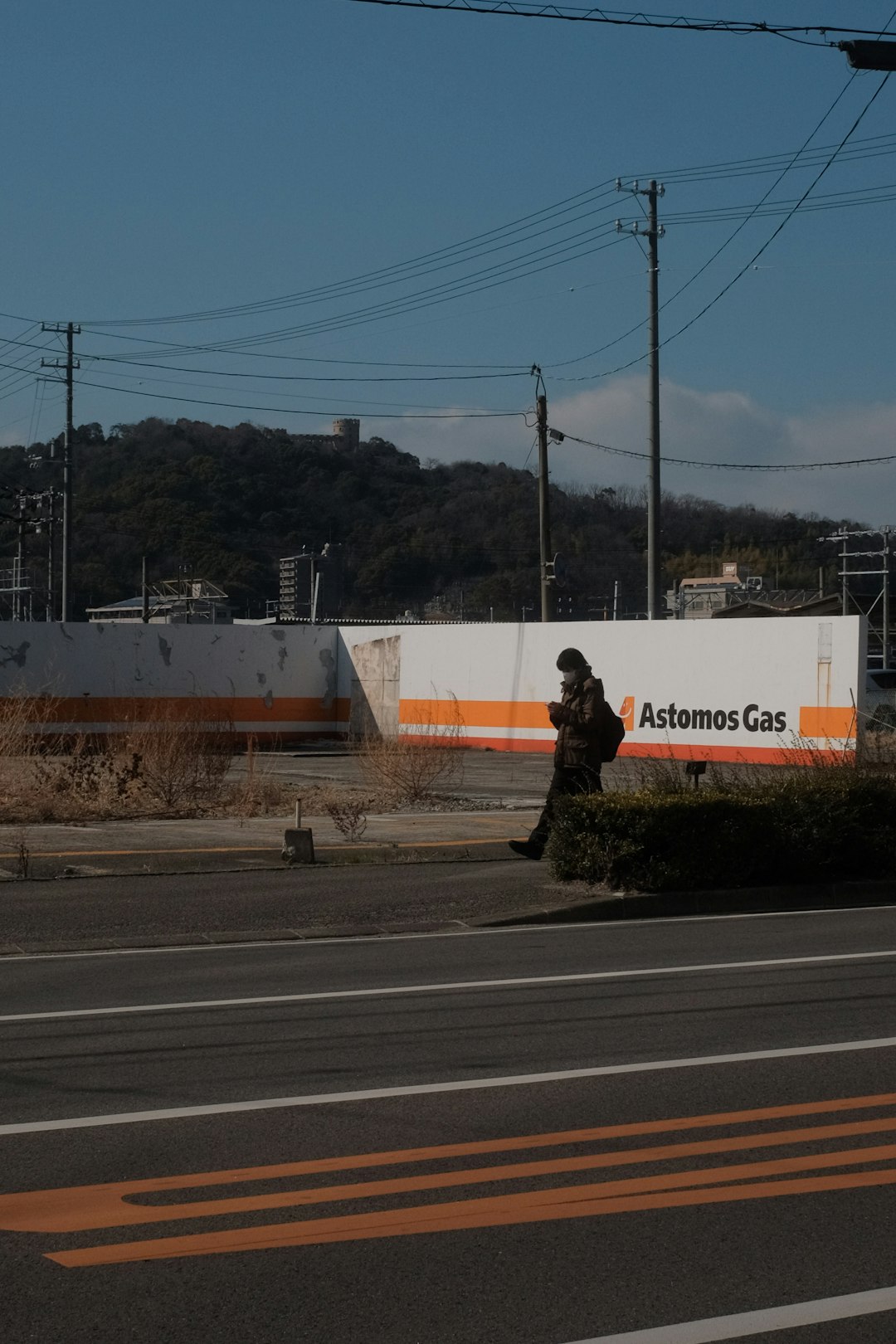 man in black jacket sitting on the edge of the road during daytime