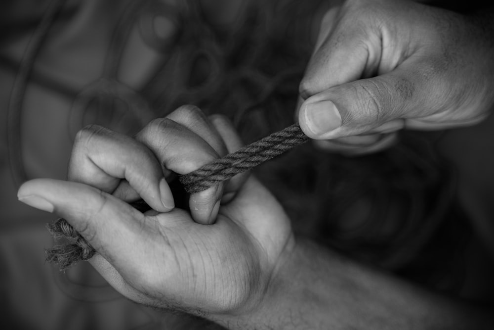 Foto in scala di grigi di una persona che tiene la corda