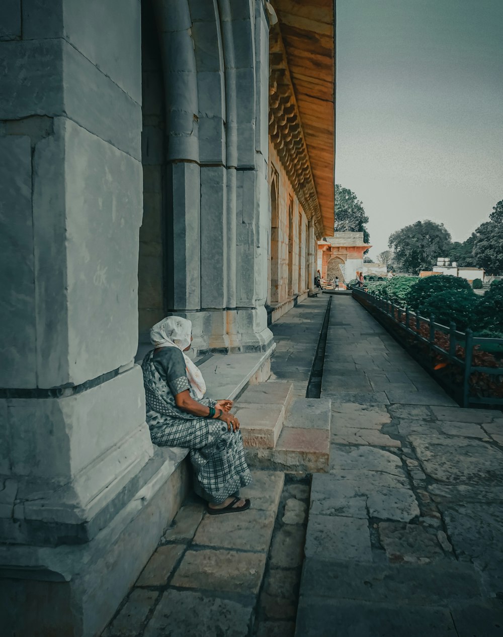 woman in black and white dress sitting on concrete bench during daytime