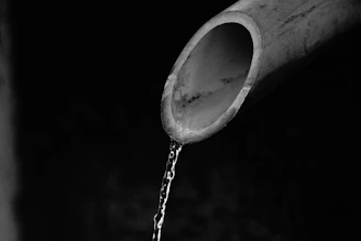 A close-up of a plumber fixing a water pipe with a wrench, water droplets visible.