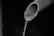 A close-up view of a partially visible pipe with water flowing out of its open end, set against a dark, indistinct background.