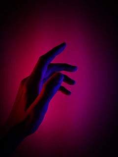 A futuristic robot hand reaching out, illuminated by vibrant purple and orange hues.
