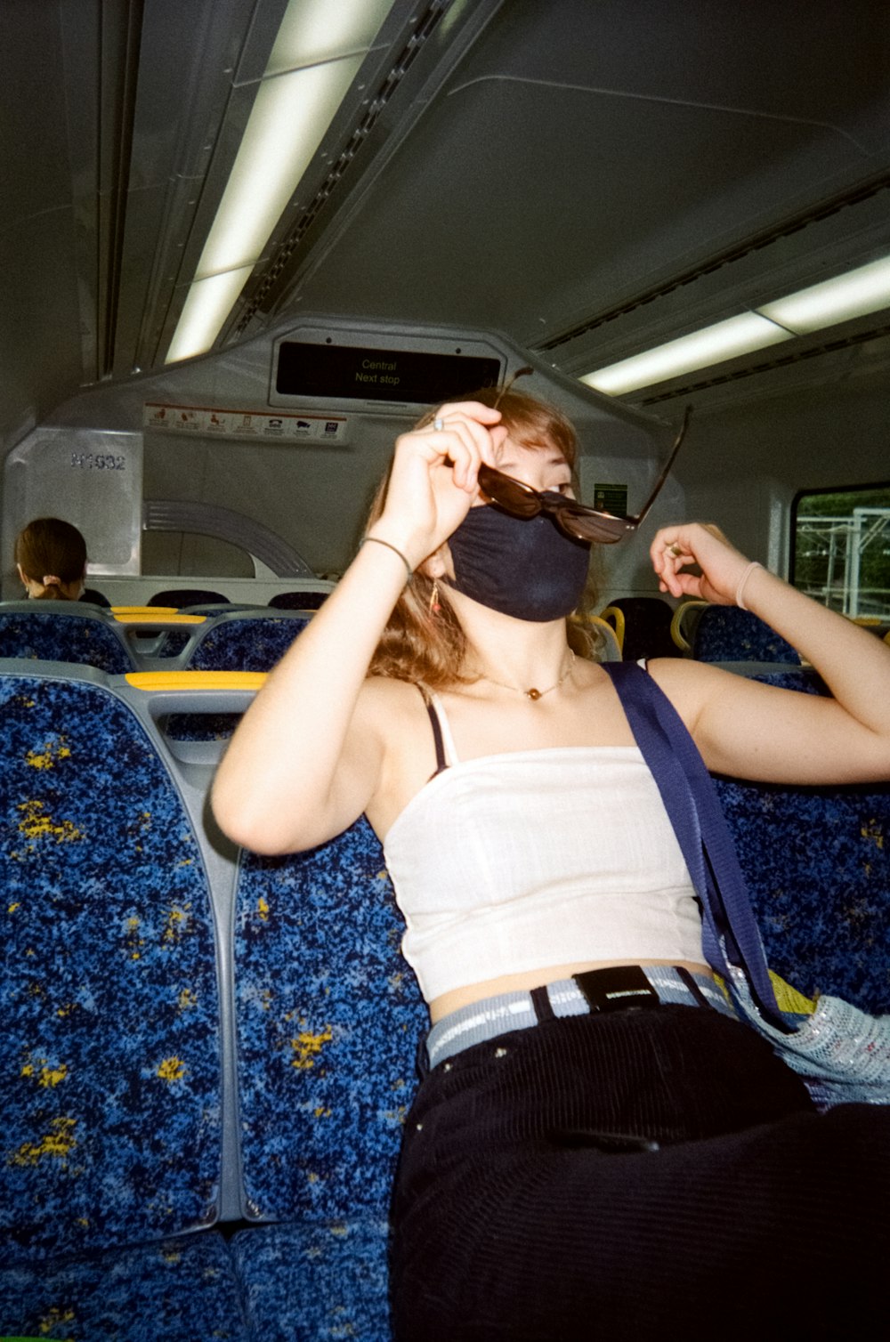 woman in white tank top and blue denim shorts sitting on blue bus seat