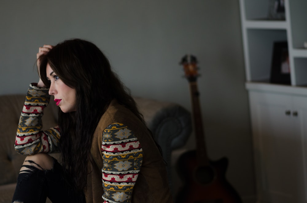 woman in black and red floral long sleeve shirt sitting on brown sofa