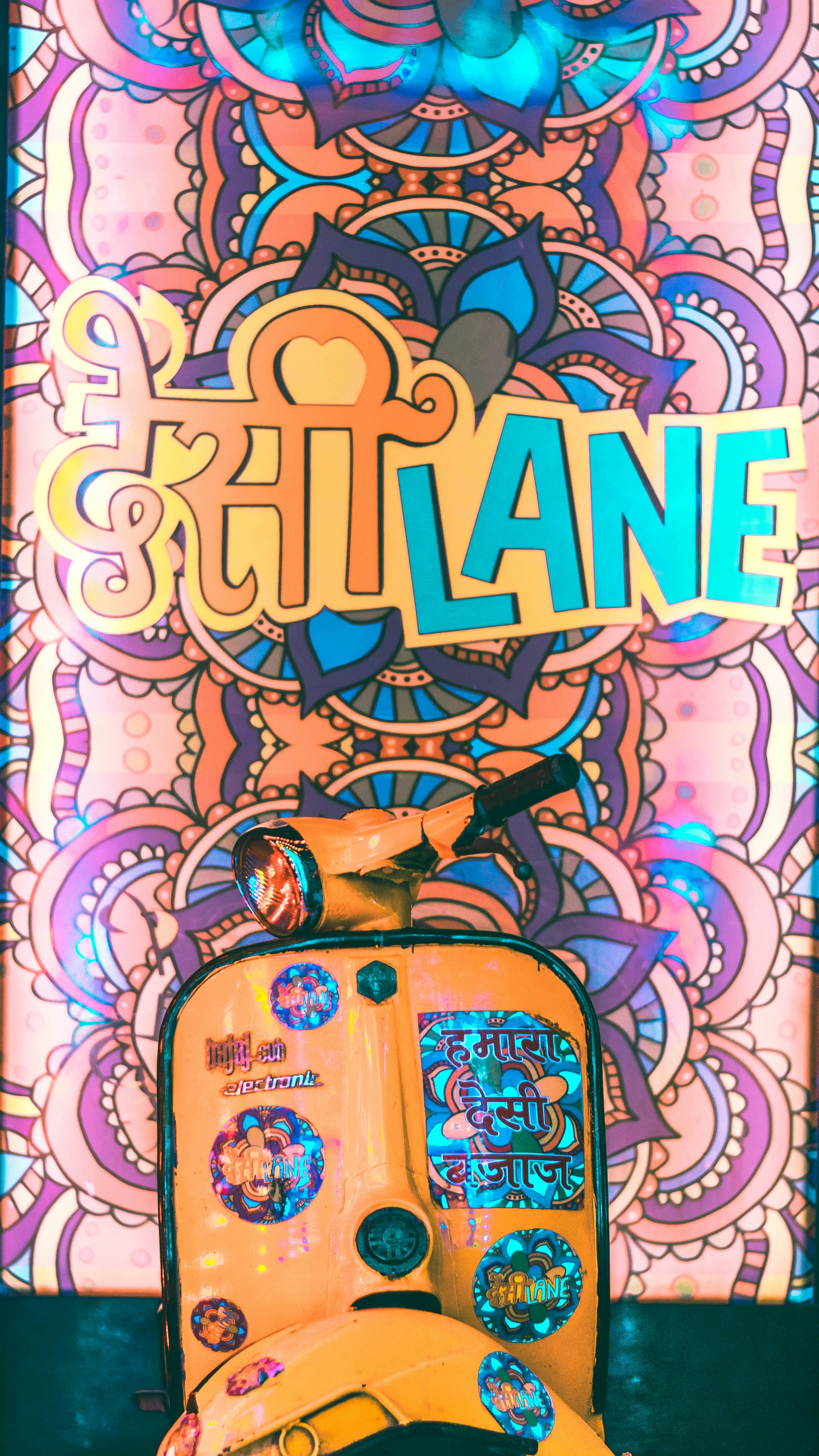 a yellow scooter parked in front of a colorful wall