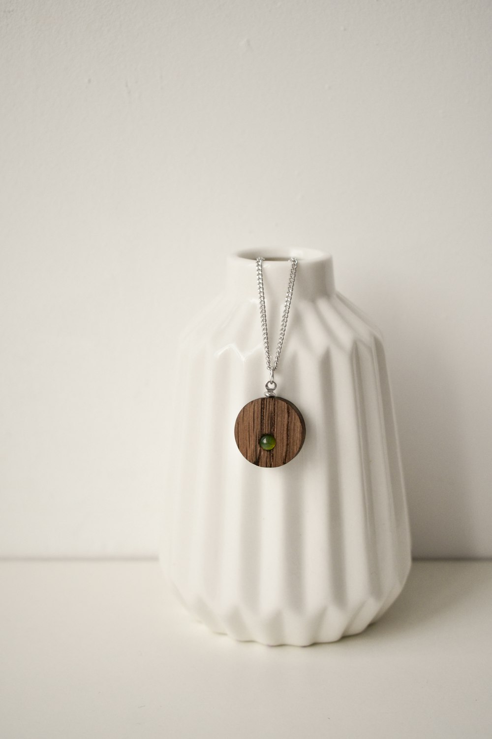 gold round pendant necklace on white textile
