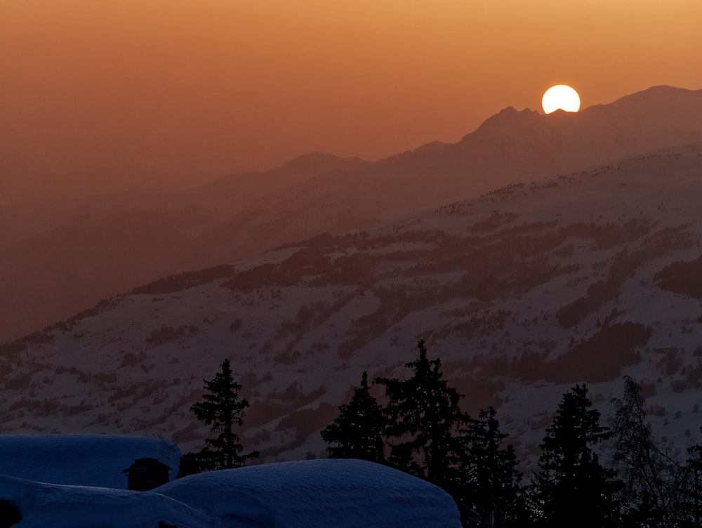 silhueta de árvores e montanhas durante o pôr do sol