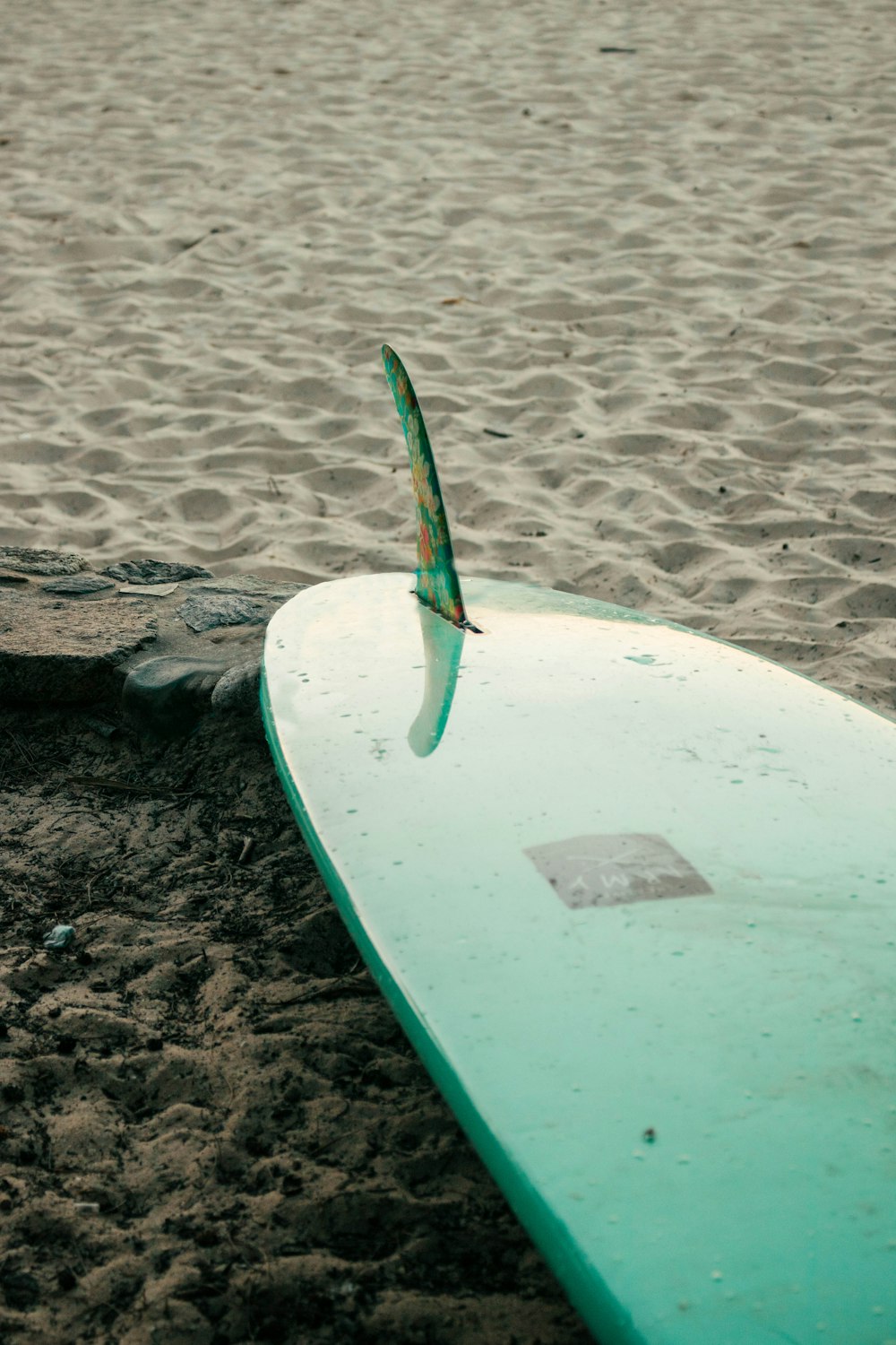 tavola da surf verde e bianca su sabbia marrone