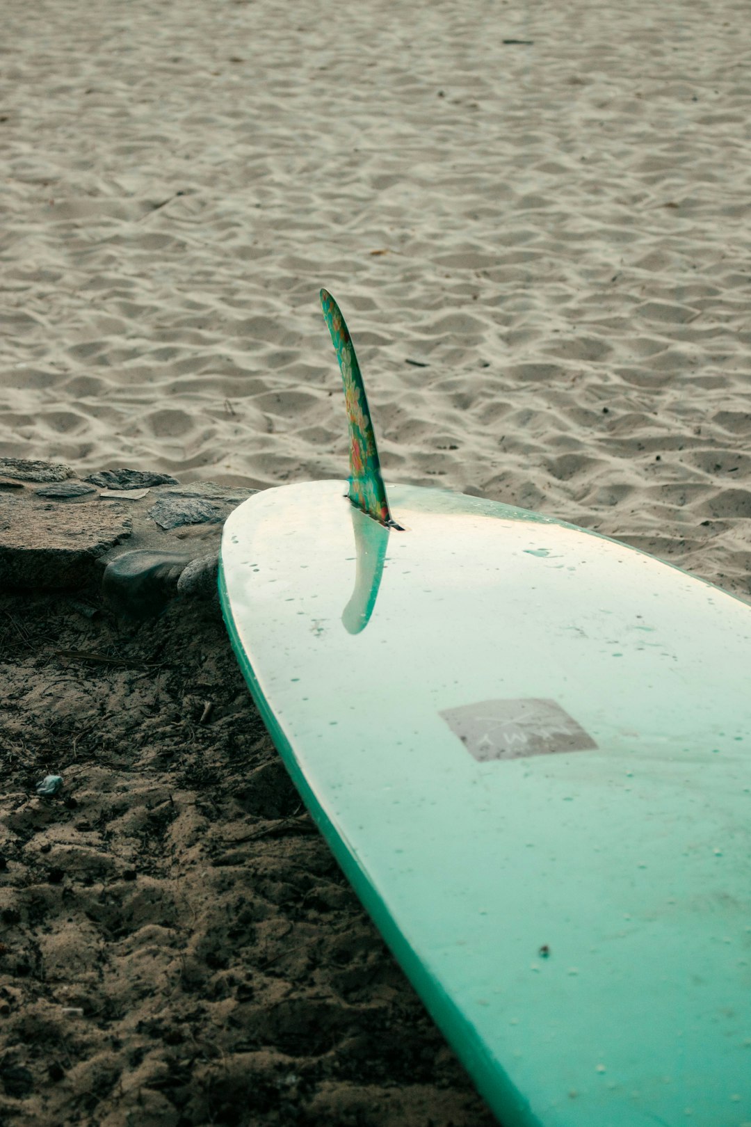 green and white surfboard on brown sand