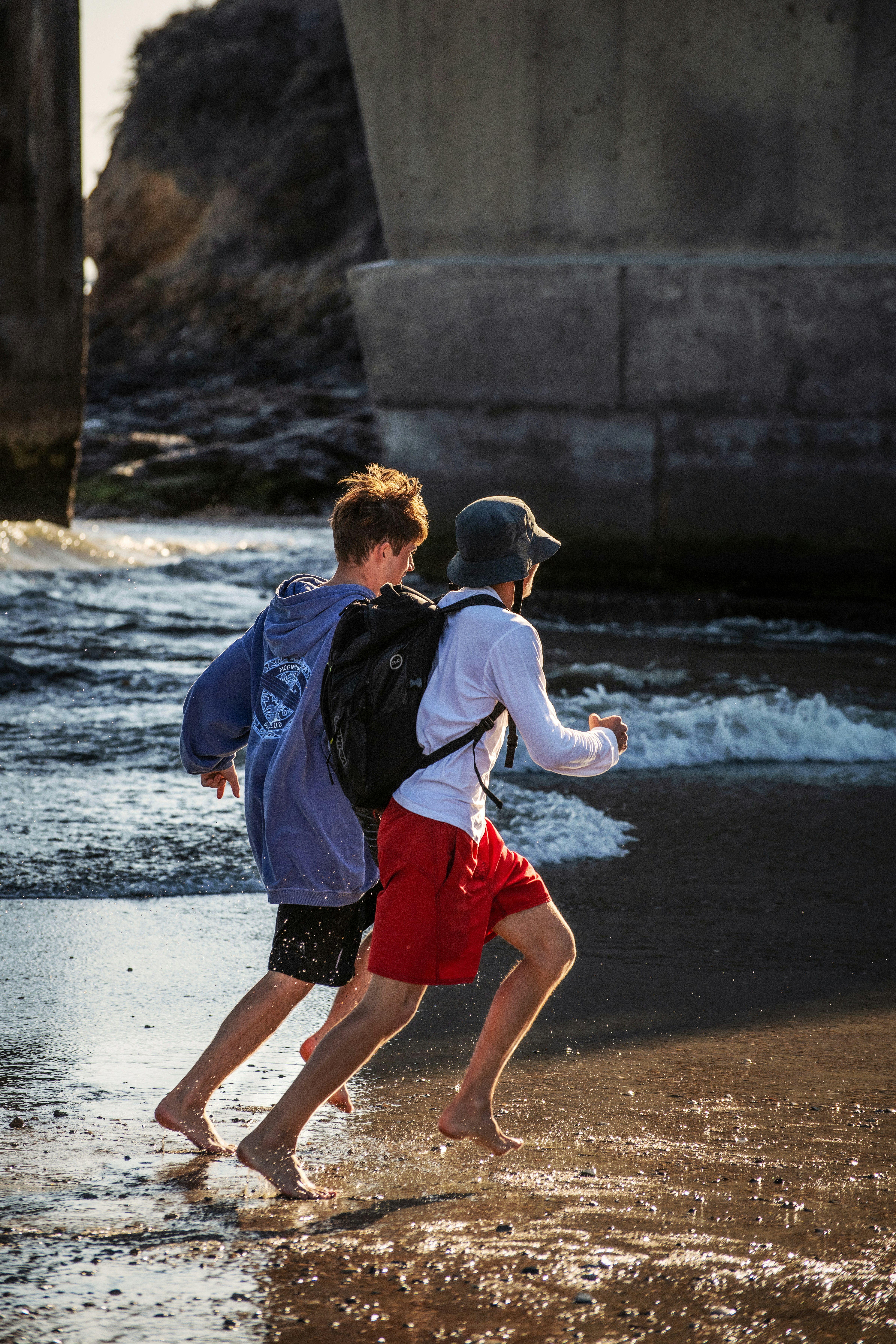 man in blue jacket and red shorts walking on beach during daytime