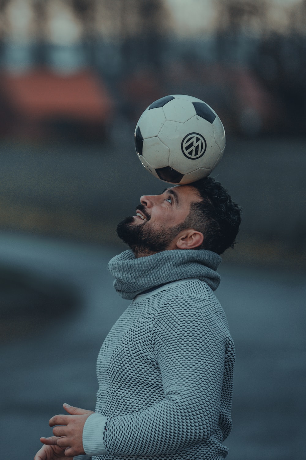 man in gray coat holding soccer ball