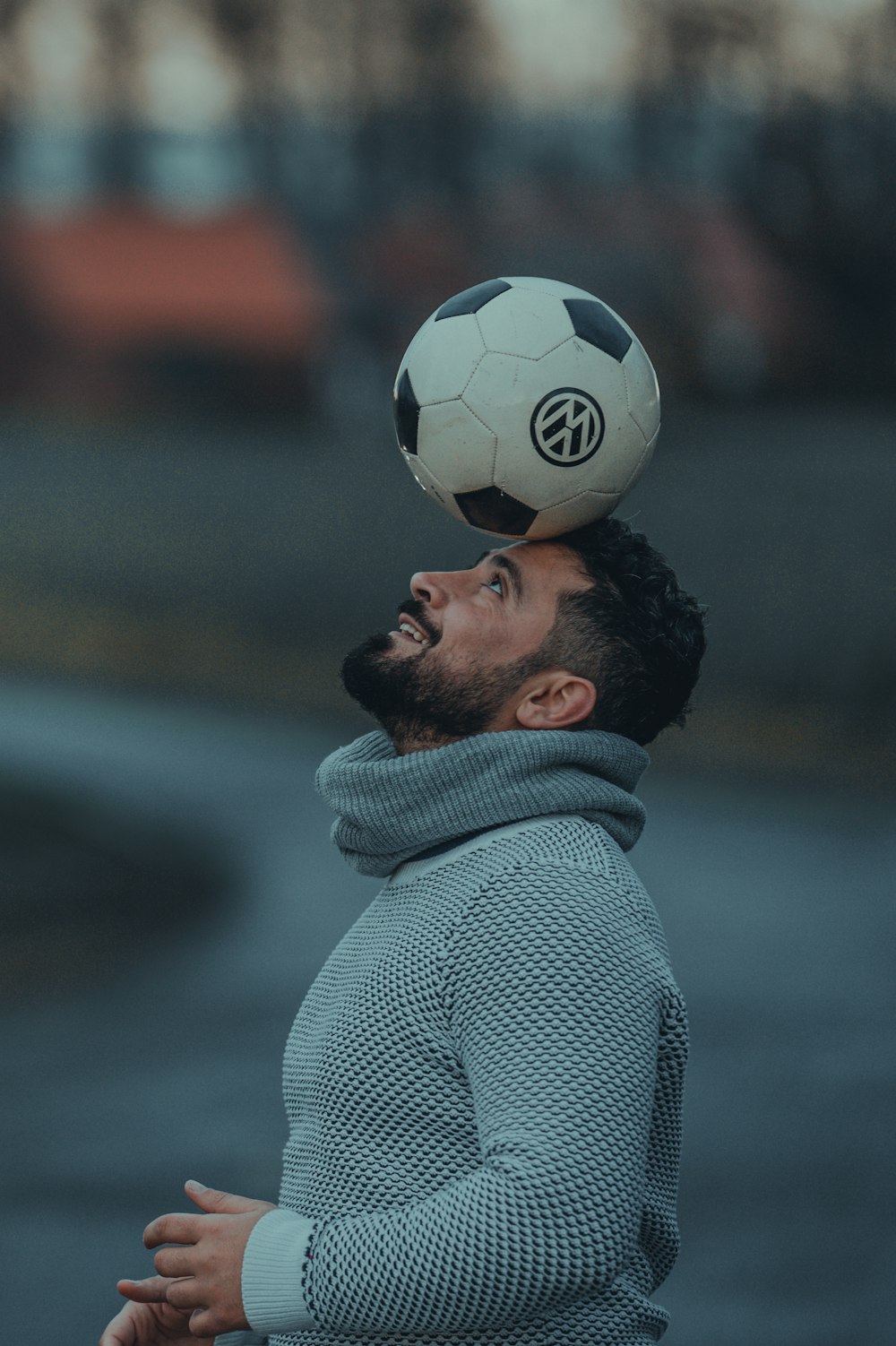 man in gray coat holding soccer ball