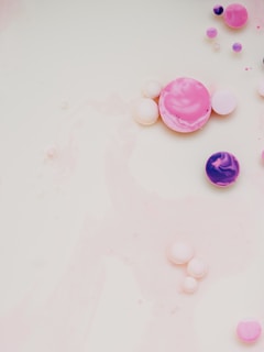 A playful mix of pastel pink and purple slime with foam beads on a white surface
